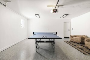 Ein Zimmer mit einem Tischtennis-Tisch, einer Tür, einem gemusterten Teppich und einer Couch.