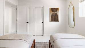 A hotel room with two beds, a door, a wall-mounted mirror, and a piece of abstract art. - LUXE - SOTO Luxury House in Old Town Scottsdale (Scottsdale)
