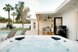 A hot tub with a patio area, a dining table, and chairs. - SOTO: Scottsdale Home, Pool, Spa & Putting Green (Scottsdale)
