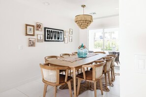 A dining area with a wooden table and chairs, a chandelier, and framed pictures on the wall. - SOTO: Scottsdale Home, Pool, Spa & Putting Green (Scottsdale)