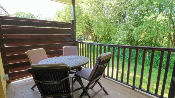 A covered outdoor seating area with a table and chairs, a wooden fence, and a view of greenery. - 7 Brunston Avenue (Girvan)
