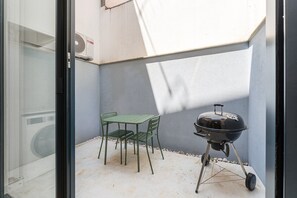 A small outdoor patio with a grill, a table, and two chairs. - GuestReady-Charming Aveiro Home (Aveiro)