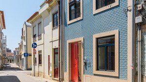 A street view with buildings featuring blue and beige facades, a red door, and a clear sky. - GuestReady-Charming Aveiro Home (Aveiro)