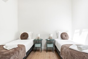 A hotel room with two beds, each with a pillow and a bedside table with a lamp. - GuestReady-Charming Aveiro Home (Aveiro)