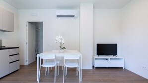 Eine moderne Küche mit weißen Schränken und einem Essbereich mit weißem Tisch und Stühlen.