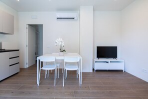 Eine moderne Küche mit weißen Schränken und einem Essbereich mit weißem Tisch und Stühlen.