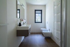 Une salle de bain moderne équipée d’un meuble-lavabo, de toilettes et d’un bidet.