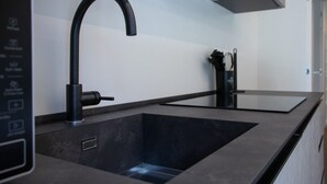 Eine moderne Küche mit einem schwarzen Wasserhahn, einer integrierten Spüle und einer Dunstabzugshaube.