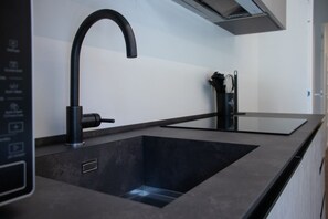 Eine moderne Küche mit einem schwarzen Wasserhahn, einer integrierten Spüle und einer Dunstabzugshaube.