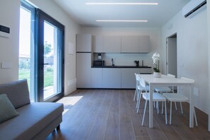 Una cocina moderna con armarios blancos, un comedor con sillas blancas y un sofá.