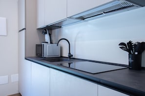 A modern kitchen with a built-in microwave, a sink, and a ventilation hood. - GuestHost - Lovely Apartment with Parking (Venturelli-Fenili)