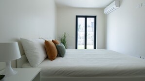 Ein Schlafzimmer mit Bett, Kissen, Nachttisch und Fenster.