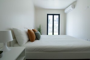 Ein Schlafzimmer mit Bett, Kissen, Nachttisch und Fenster.