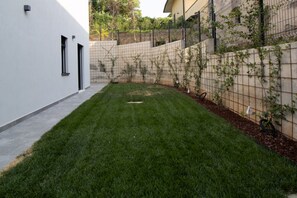 A modern building with a white exterior, a paved pathway, and a well-maintained grassy area. - GuestHost - Lovely Apartment with Parking (Venturelli-Fenili)
