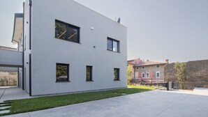 Ein modernes Gebäude mit flacher Fassade, zahlreichen Fenstern und einem gepflasterten Innenhof.