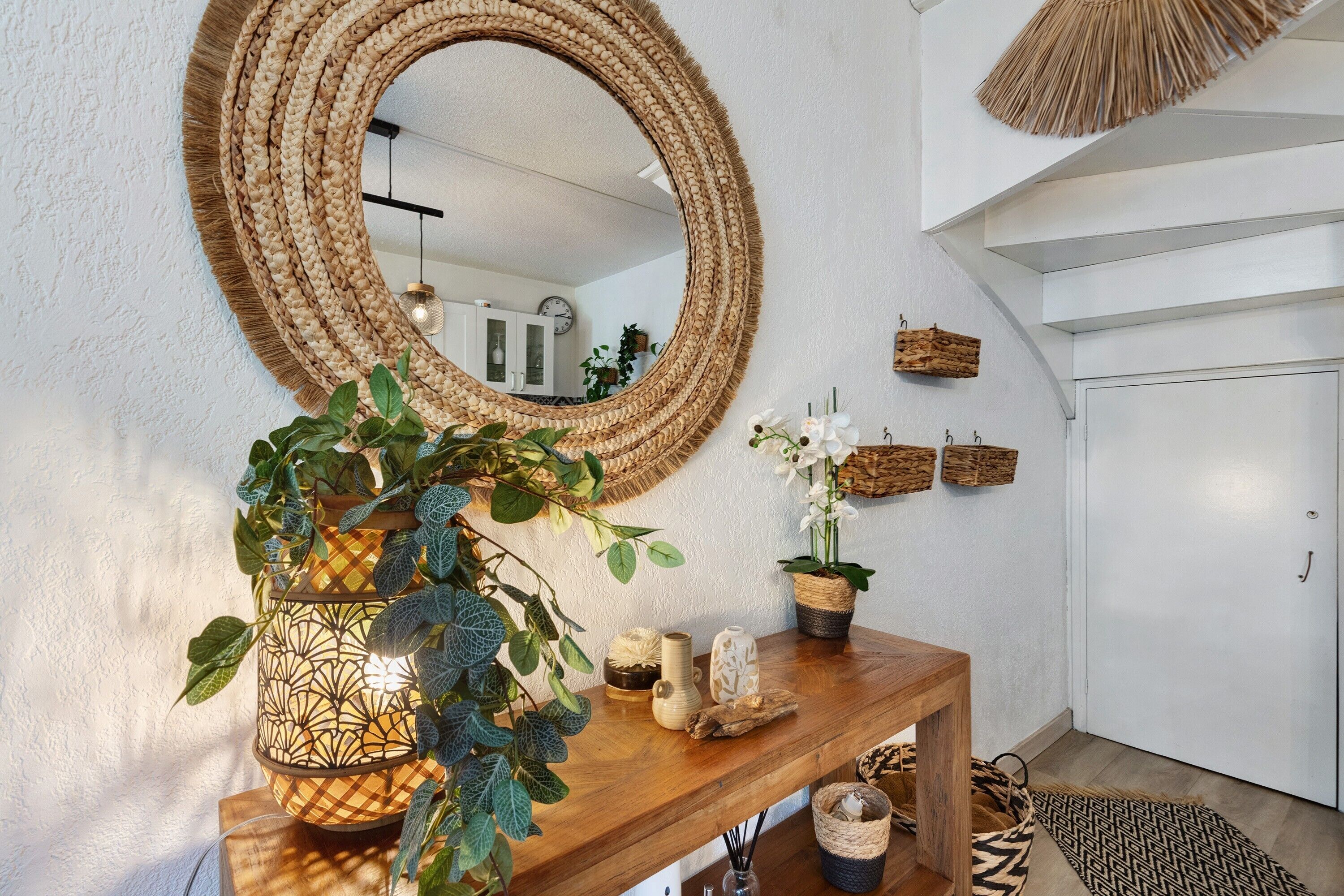 A wooden console table with a mirror, potted plants, and decorative items.