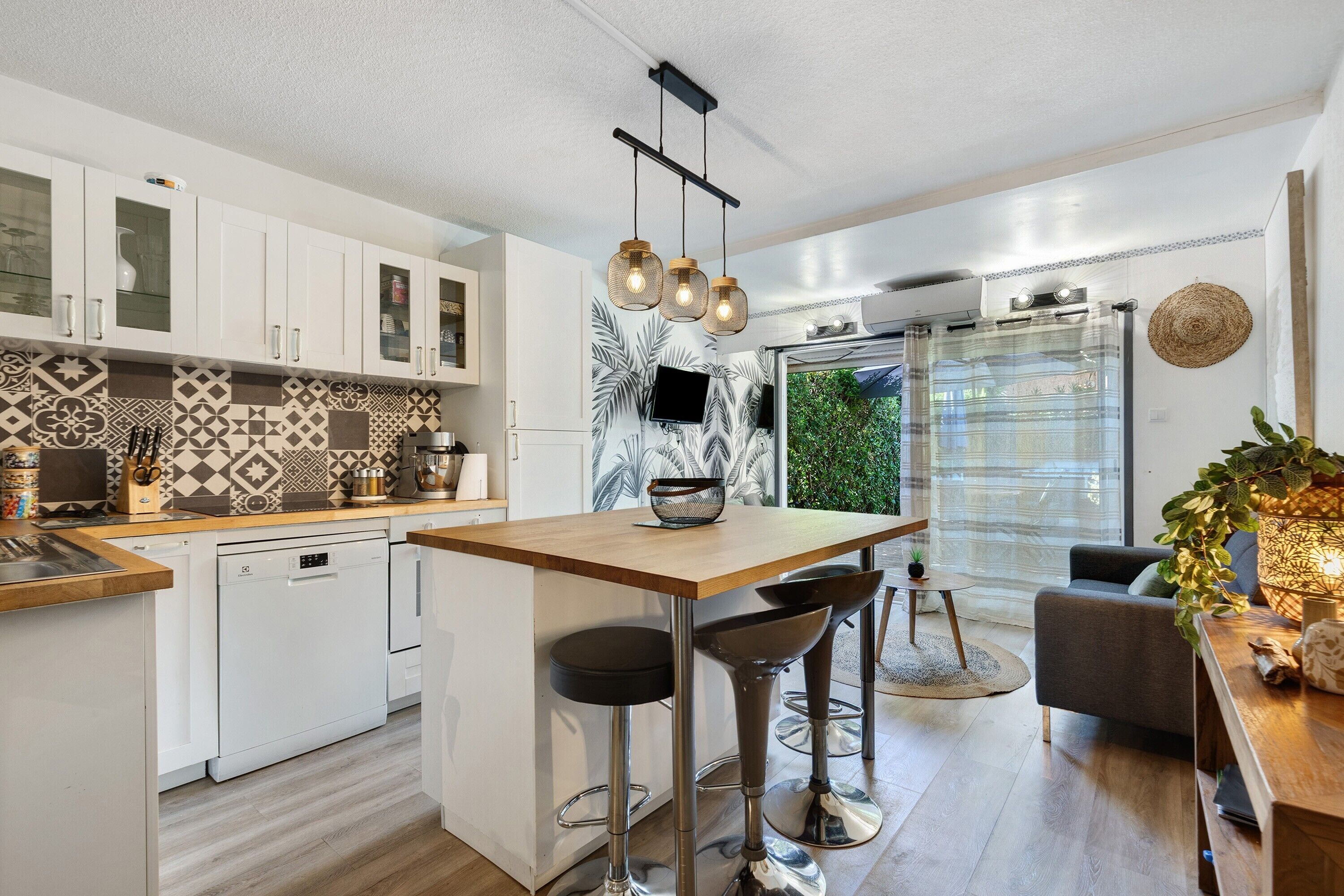 A modern kitchen with white cabinets, a wooden countertop, and a central island with bar stools.