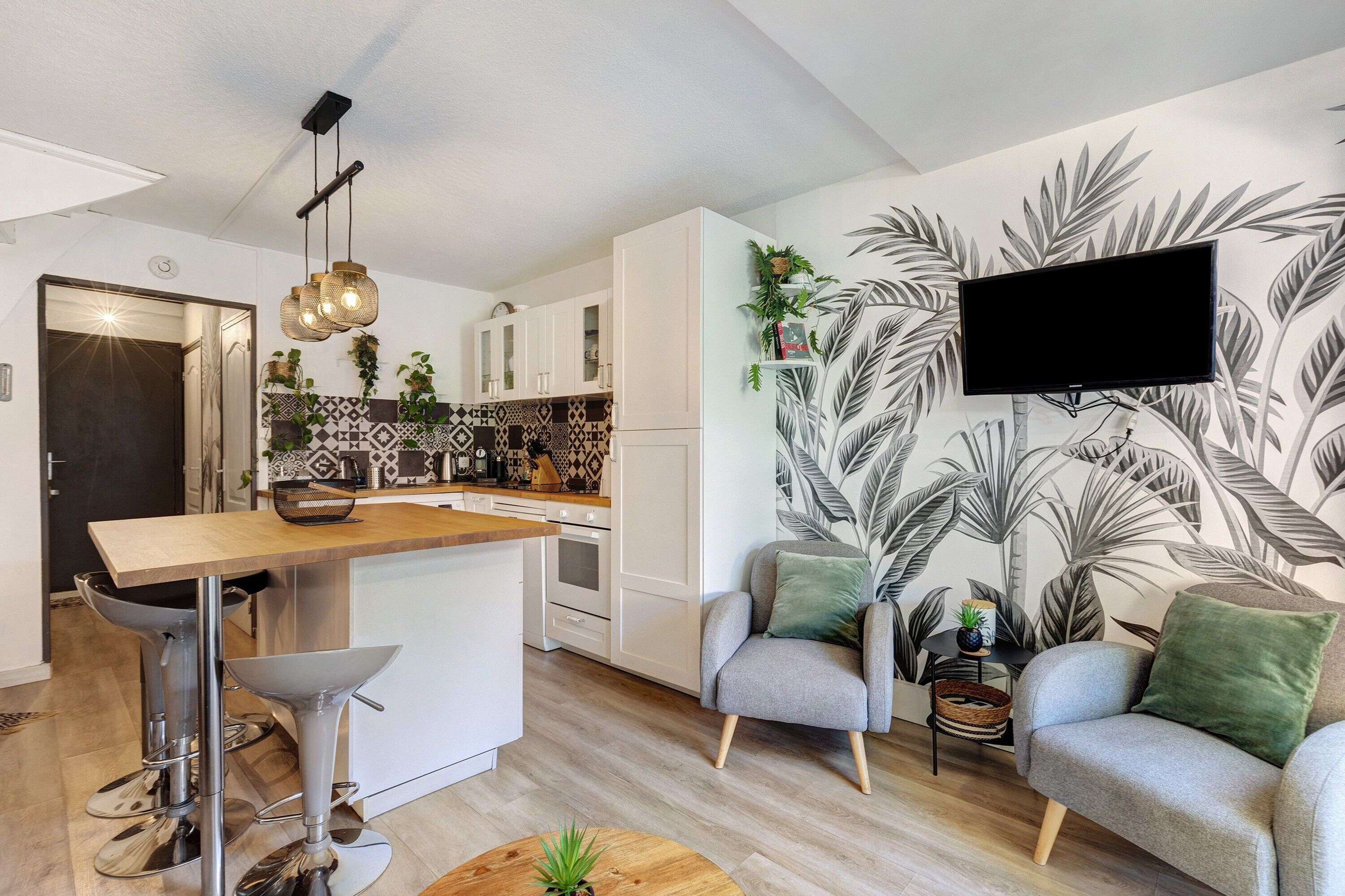 A modern kitchen with white cabinets, a wooden island, and a hanging light fixture.