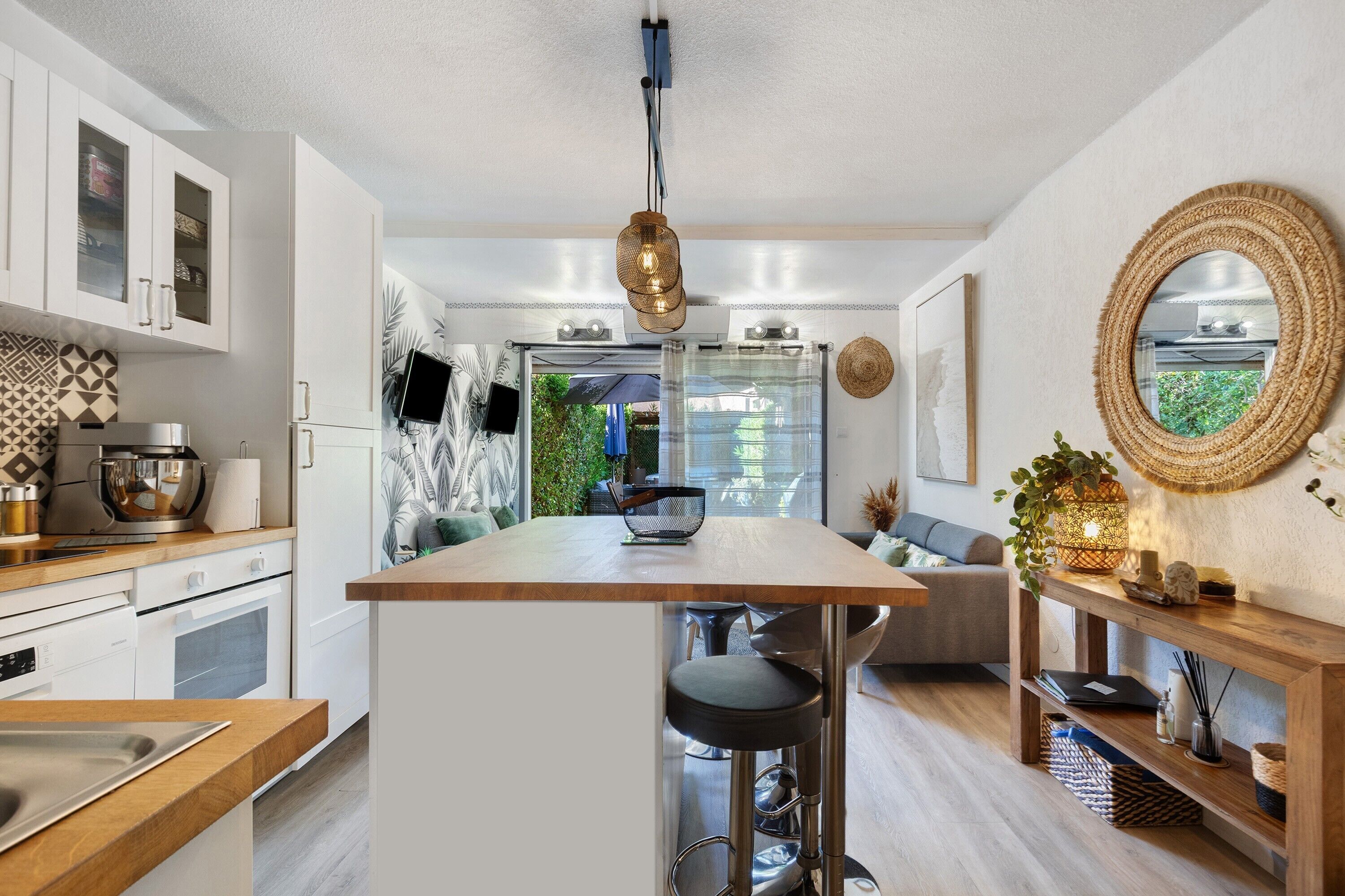 A modern kitchen with a central island, bar stools, and a dining area with a sofa.