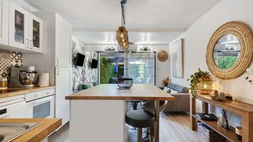 A modern kitchen with a central island, bar stools, and a dining area with a sofa.