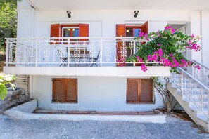 A two-story building with a balcony, a staircase, and a small garden area. - Unique Suite (Karpathos)