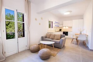 A modern living room with a sofa, a coffee table, and two ottomans. - Unique Suite (Karpathos)