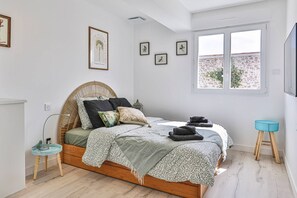 Een slaapkamer met een bed, nachtkastjes, een raam en wanddecoratie.