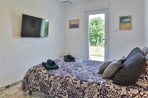 A bedroom with a bed, a television, and a door leading to an outdoor area. - Holiday home 'L’échappée Belle du Bessay' with private terrace, Wi-Fi and air conditioning (Avrillé)