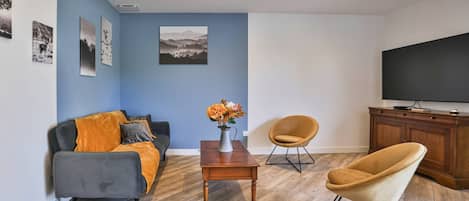Una sala de estar con un sofá, una mesa de centro, dos sillones, un televisor y un mueble.