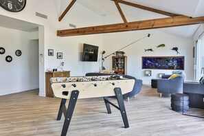 Un salon moderne avec un baby-foot, un téléviseur et un grand aquarium.