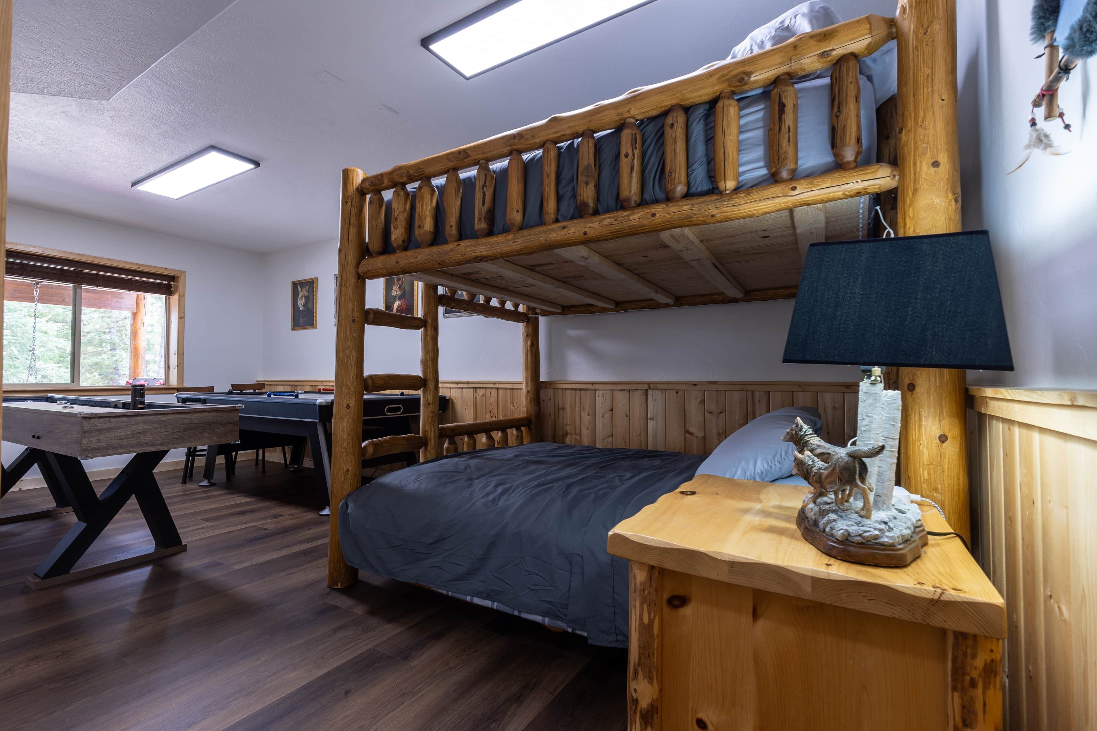 Ein Stockbett mit Holzkopfstück, ein Nachttisch mit Lampe und eine kleine Statue.