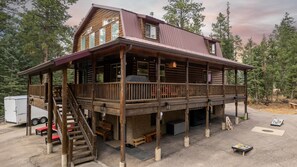 A two-story log cabin with a balcony, a covered porch, and a staircase leading to the upper level. - Rev & Rest Lodge Duck Creek (Duck Creek Village)