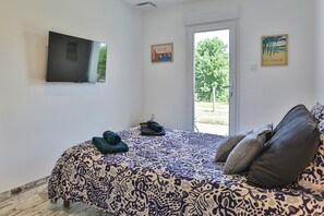 Ein Schlafzimmer mit einem Bett, einem Fernseher und einer Tür zu einem Außenbereich.