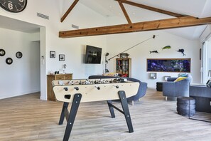 A modern living room with a foosball table, a television, and a bookshelf.