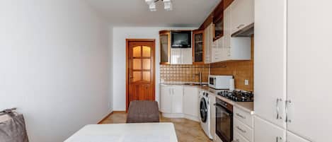 A compact kitchen with a dining area, a washing machine, and a microwave.