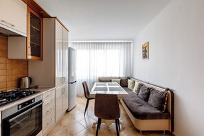 A compact kitchen with a dining area, a sofa, and a refrigerator. - 2BR • Fireplace & Panoramic Views • Near Dendrarium (Chișinău)