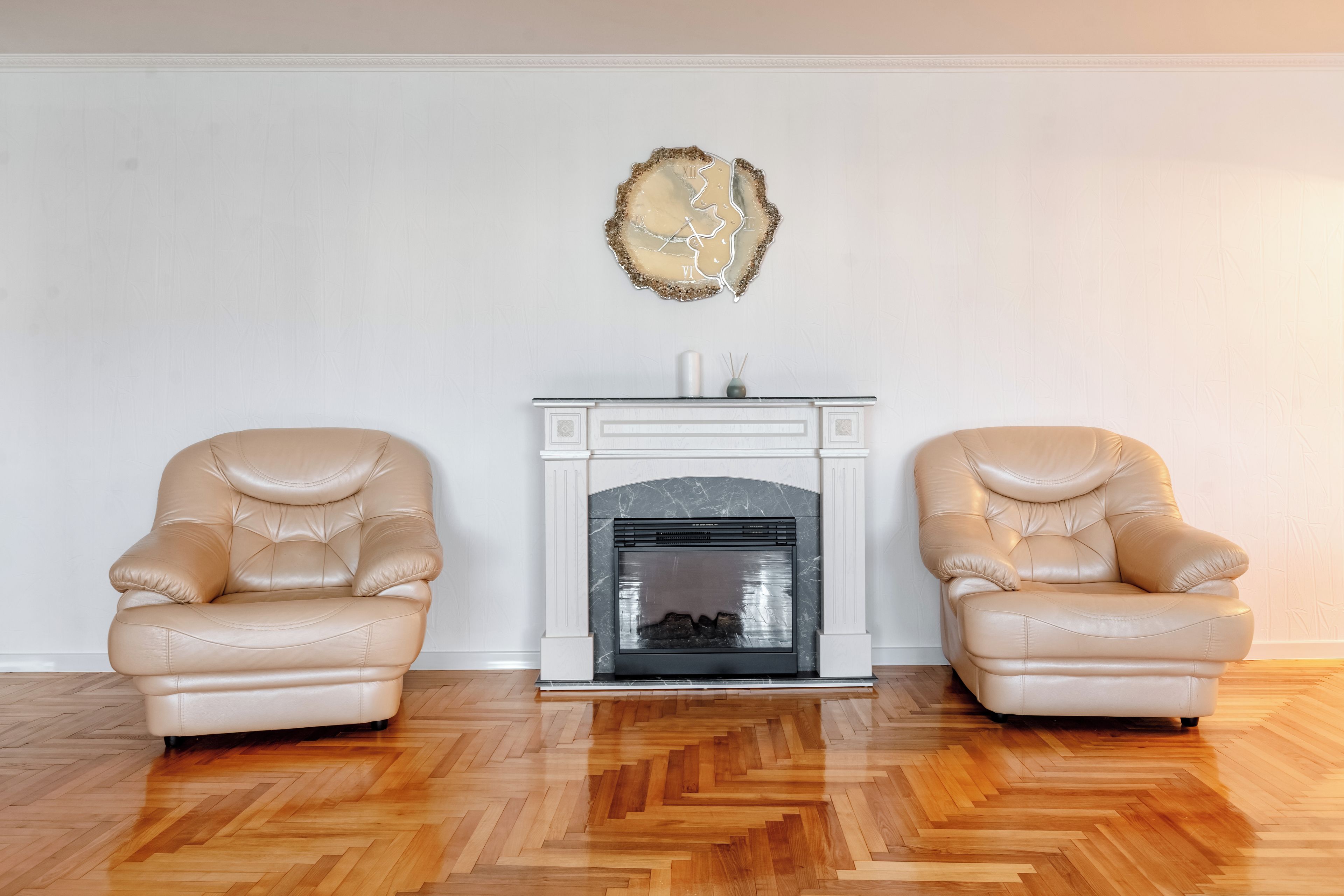 A room with a fireplace, two leather armchairs, and a decorative wall piece.