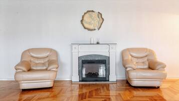 A room with a fireplace, two leather armchairs, and a decorative wall piece.