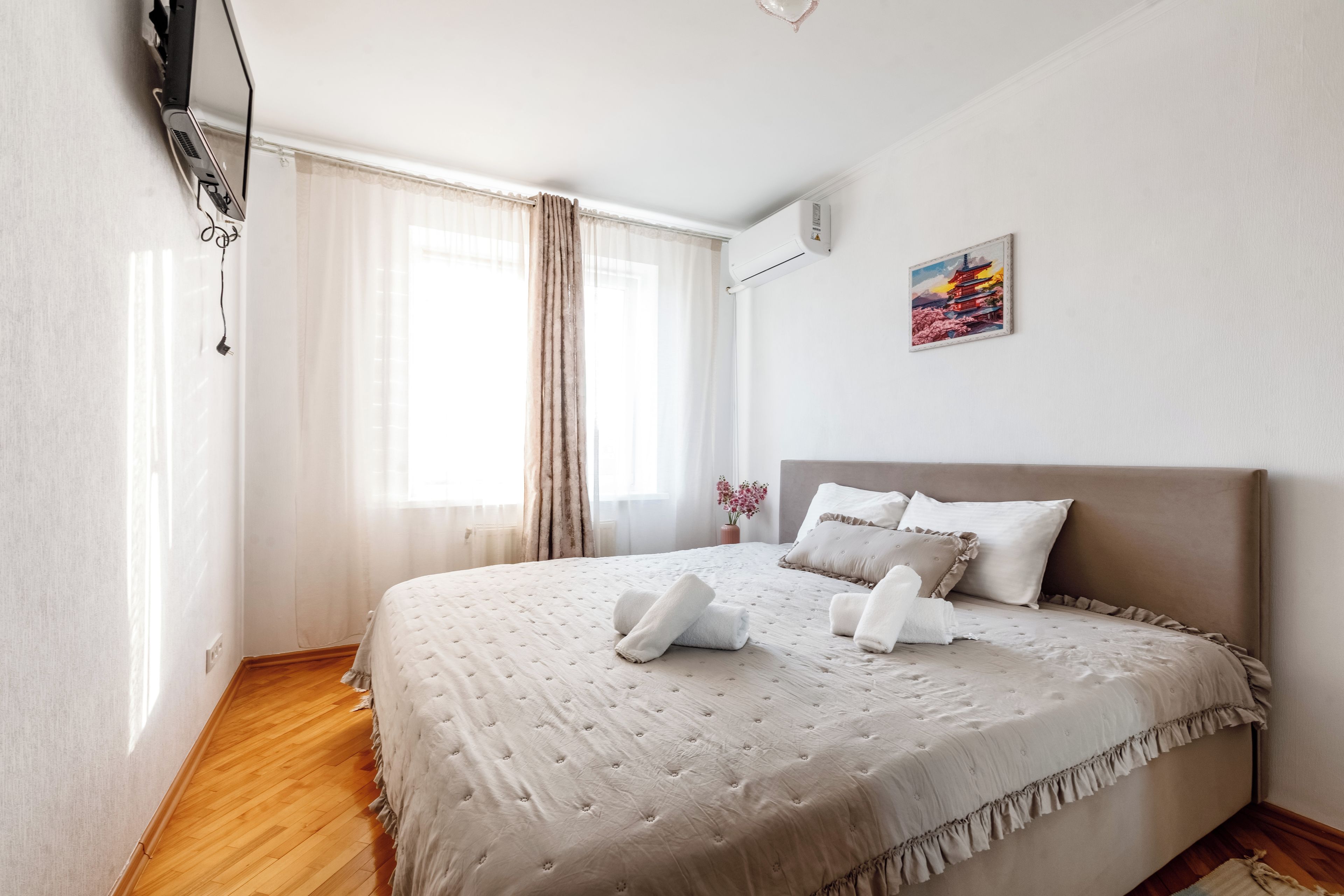 Ein Hotelzimmer mit Bett, Vorhängen, einem Gemälde und einem Fenster.