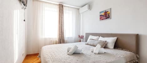 A hotel room with a bed, curtains, a painting, and a window.