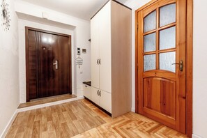 A hallway with a wooden door, a wardrobe, and a small hanging sign. - 2BR • Fireplace & Panoramic Views • Near Dendrarium (Chișinău)