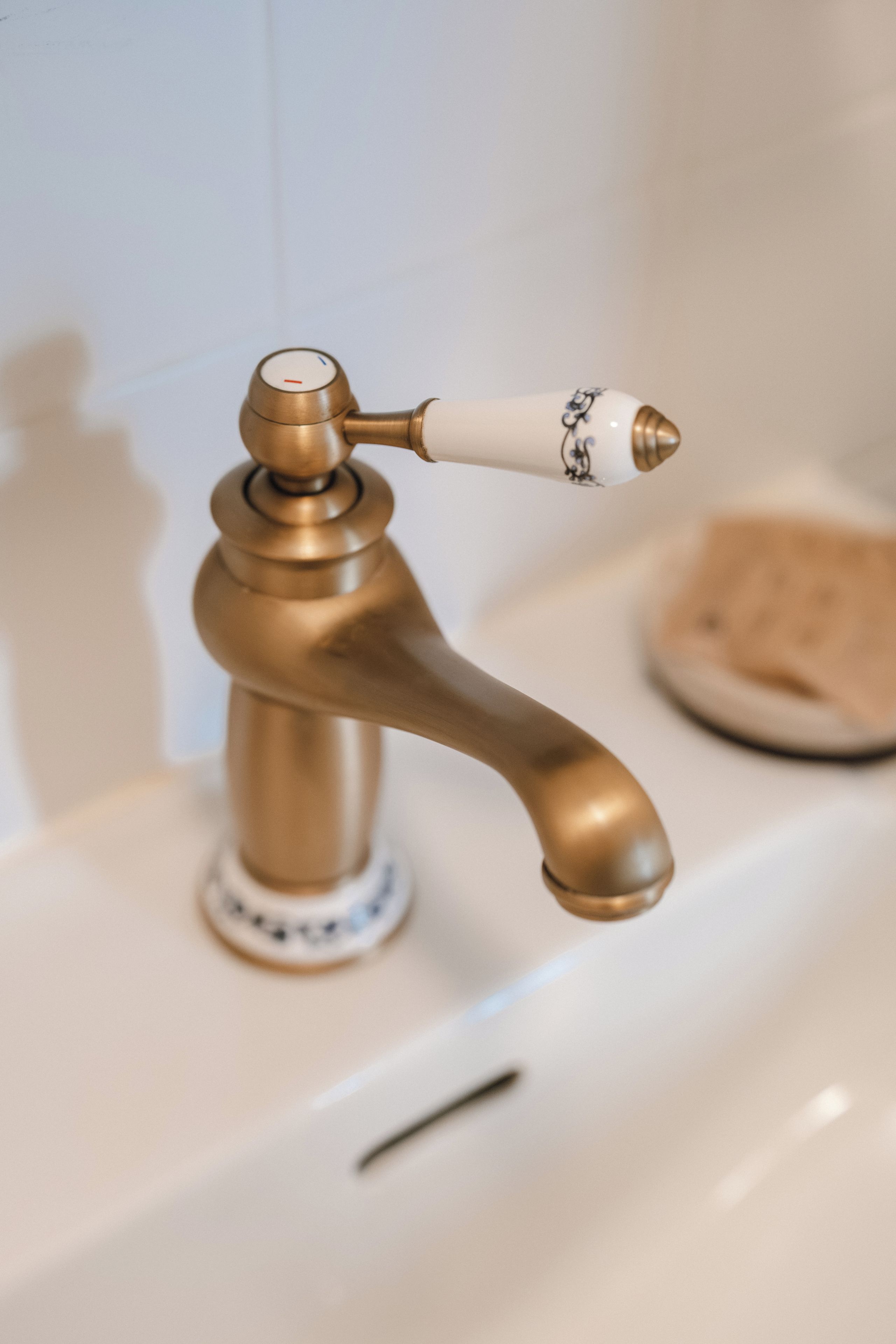 A bathroom with a brass faucet and a soap dish.