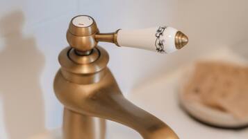 A bathroom with a brass faucet and a soap dish.
