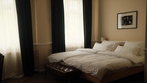 Una habitación de hotel con una cama, un banco y un cuadro en la pared.
