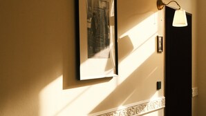 Un pasillo con un retrato en la pared, una lámpara y una puerta.