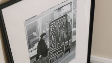 A framed photograph of a vintage bus timetable with a man standing beside it.