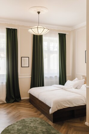 Un dormitorio con una cama grande, una lámpara colgante y cortinas verdes.