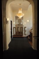 Entrada de un hotel con un candelabro, una escalera y un cartel que dice 'HOTEL DERE'.