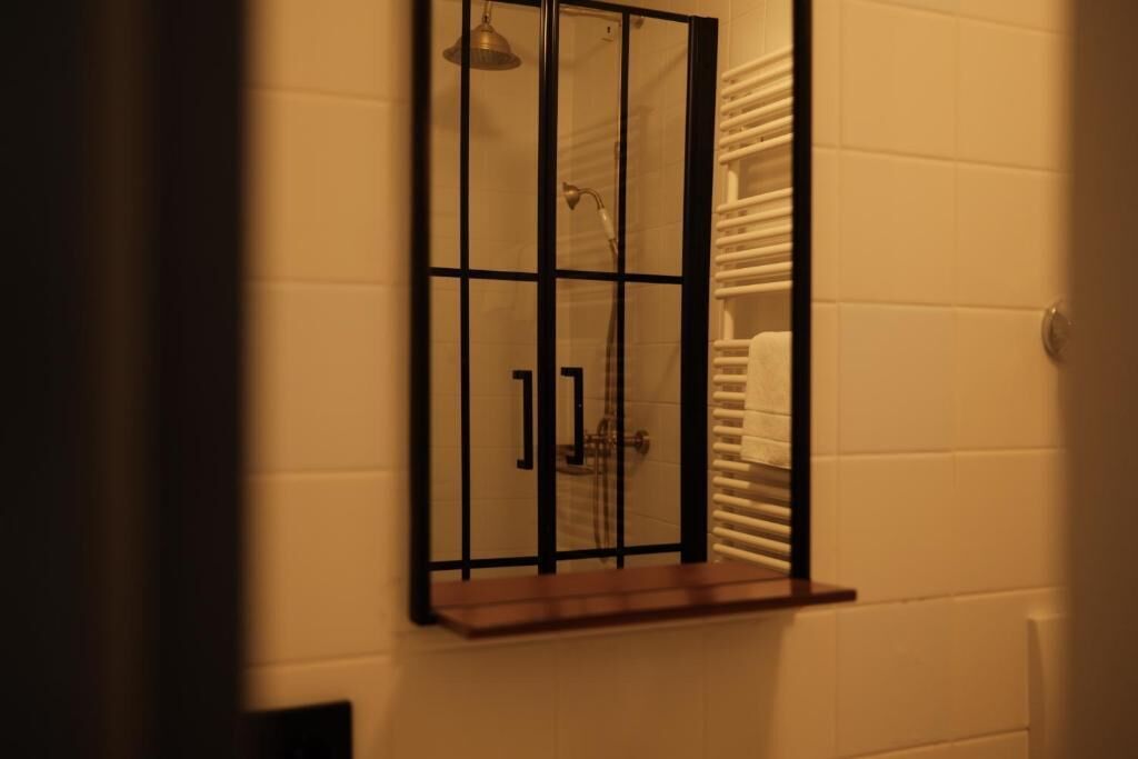 Un baño con mampara de vidrio, toallero y ducha.