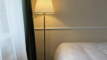 Ein Hotelzimmer mit Bett, Stehlampe und Vorhang.